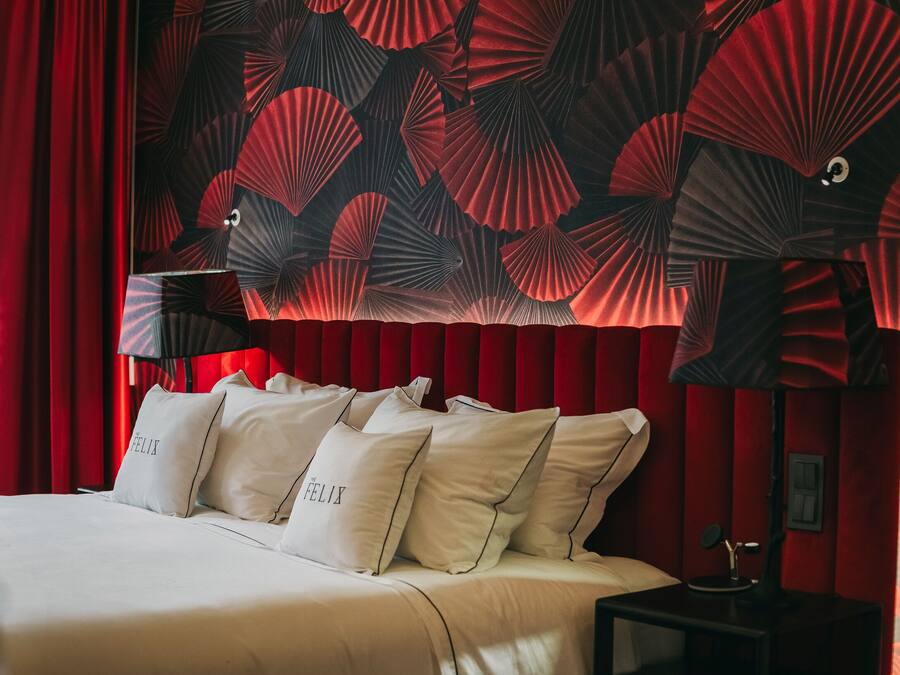 Ein Hotelzimmer mit einem großen Bett, roten Vorhängen und einer Wand mit einem Fächermuster.