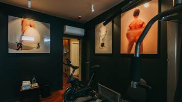 A gym with exercise bikes, a treadmill, and wall-mounted artwork.