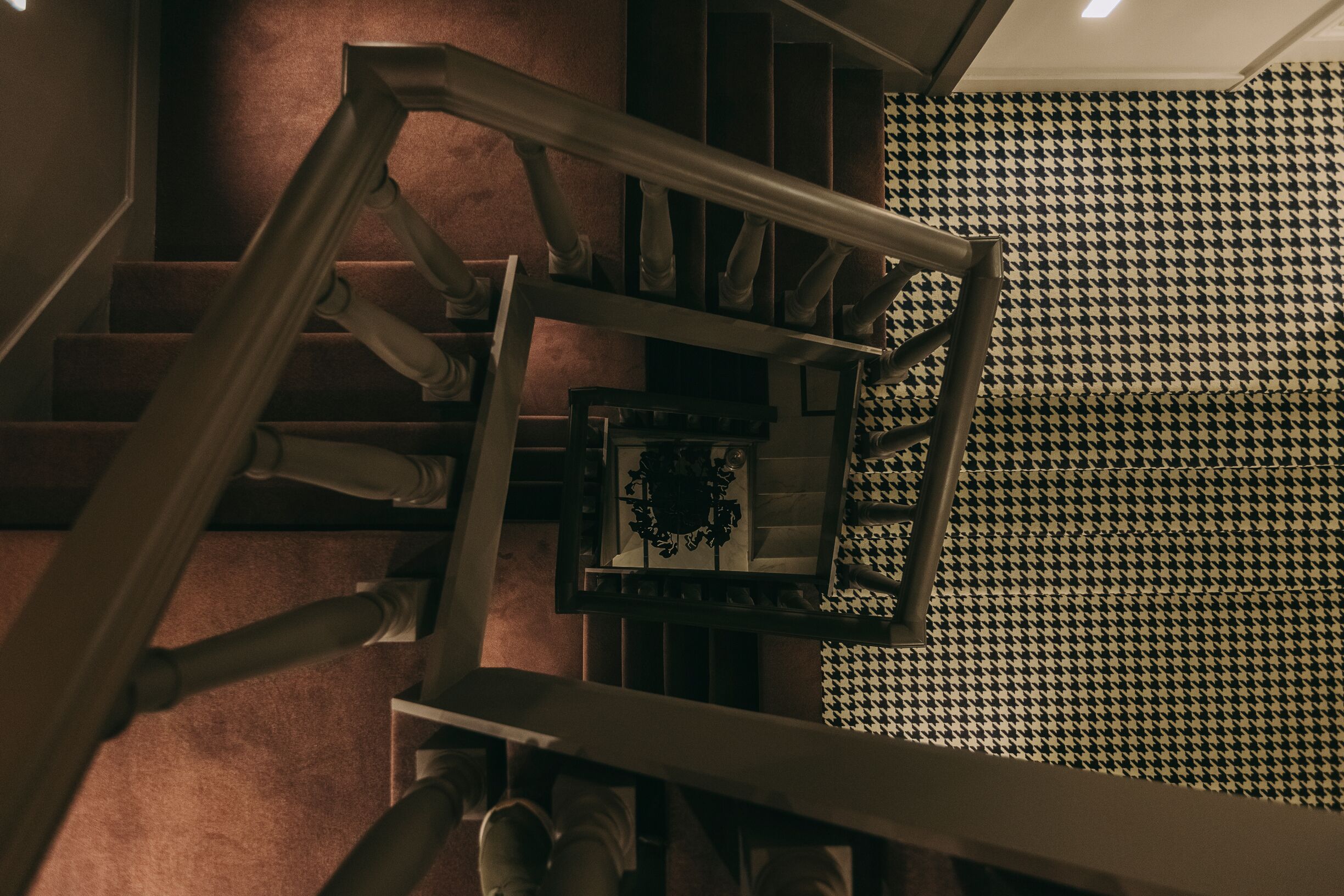 A staircase with a houndstooth patterned floor and a metal handrail.