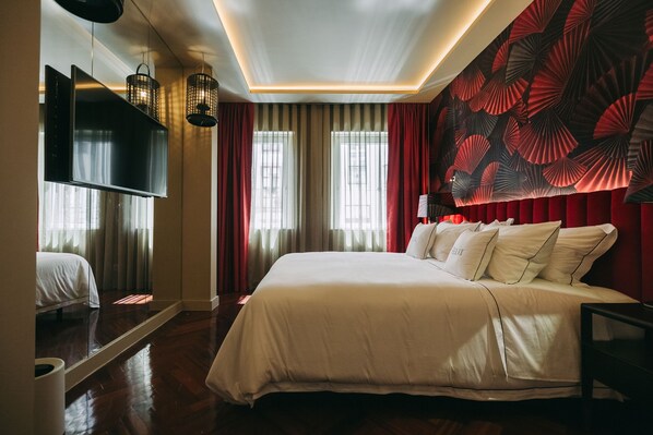 Quarto de hotel com uma cama grande, uma televisão de tela plana na parede e uma parede decorativa com padrão de leque.