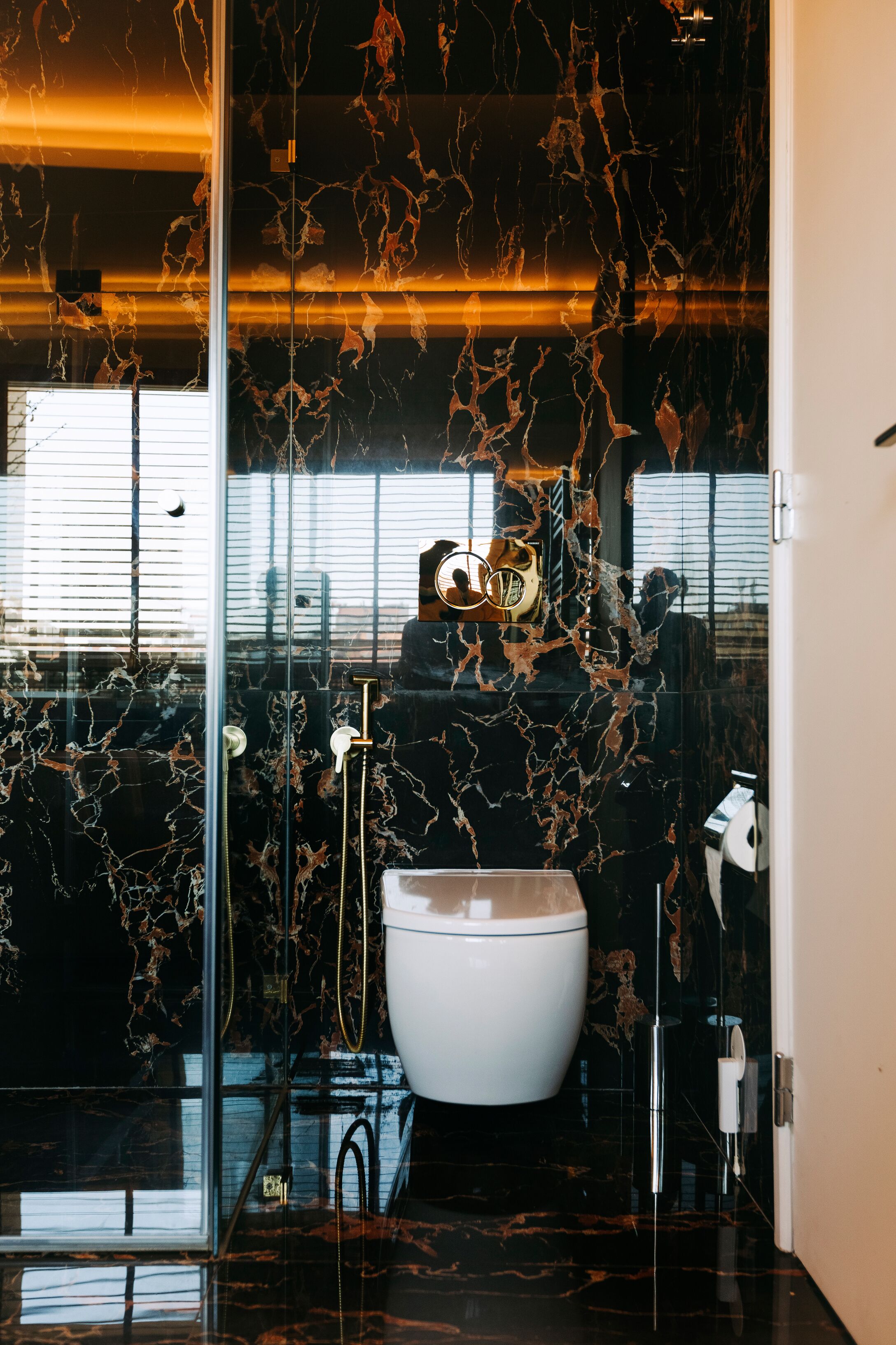 Une salle de bain moderne avec une paroi de douche en verre, des toilettes blanches et un pare-baignoire en marbre.