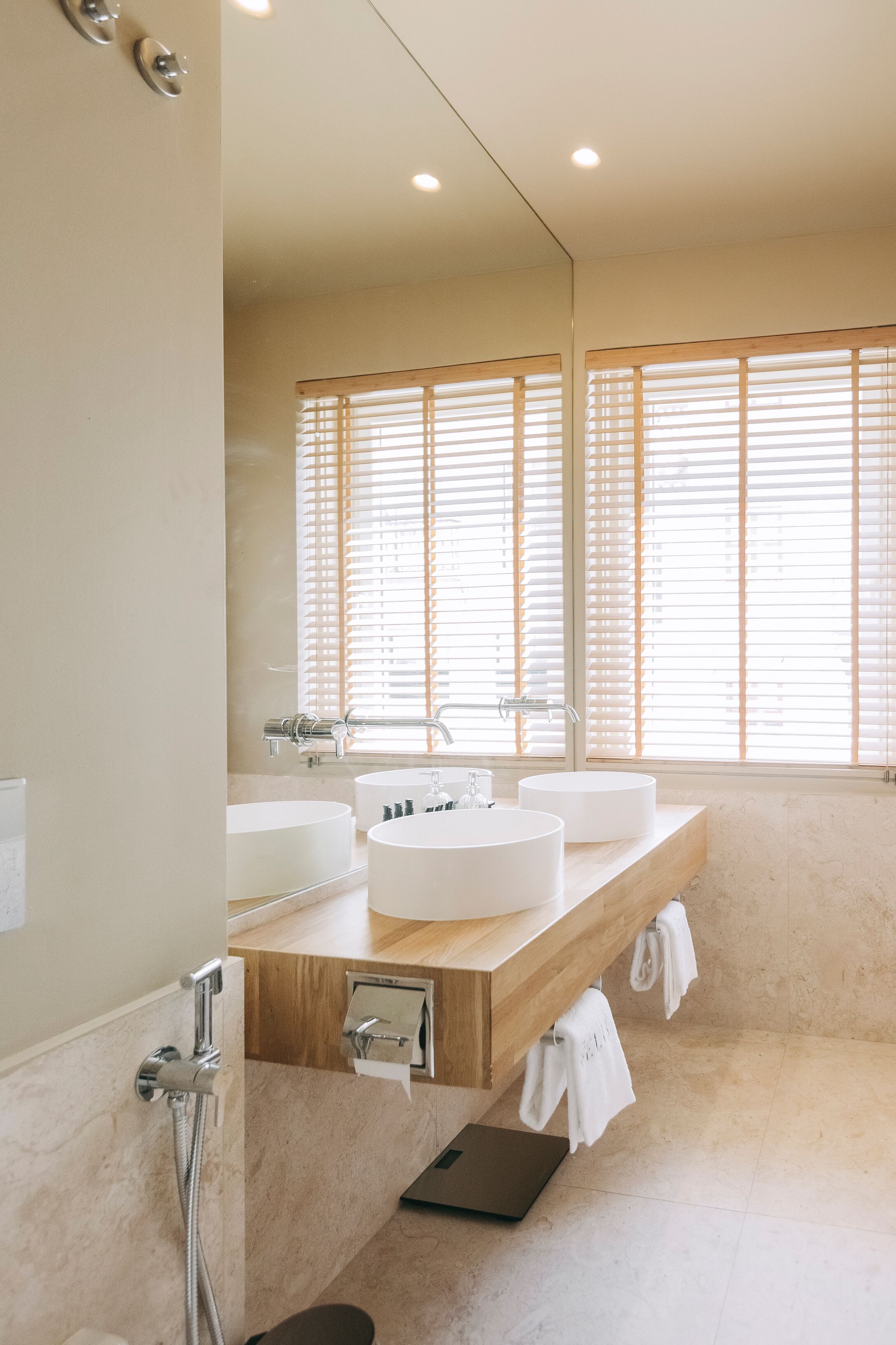A modern bathroom with two sinks, a large mirror, and a shower area.