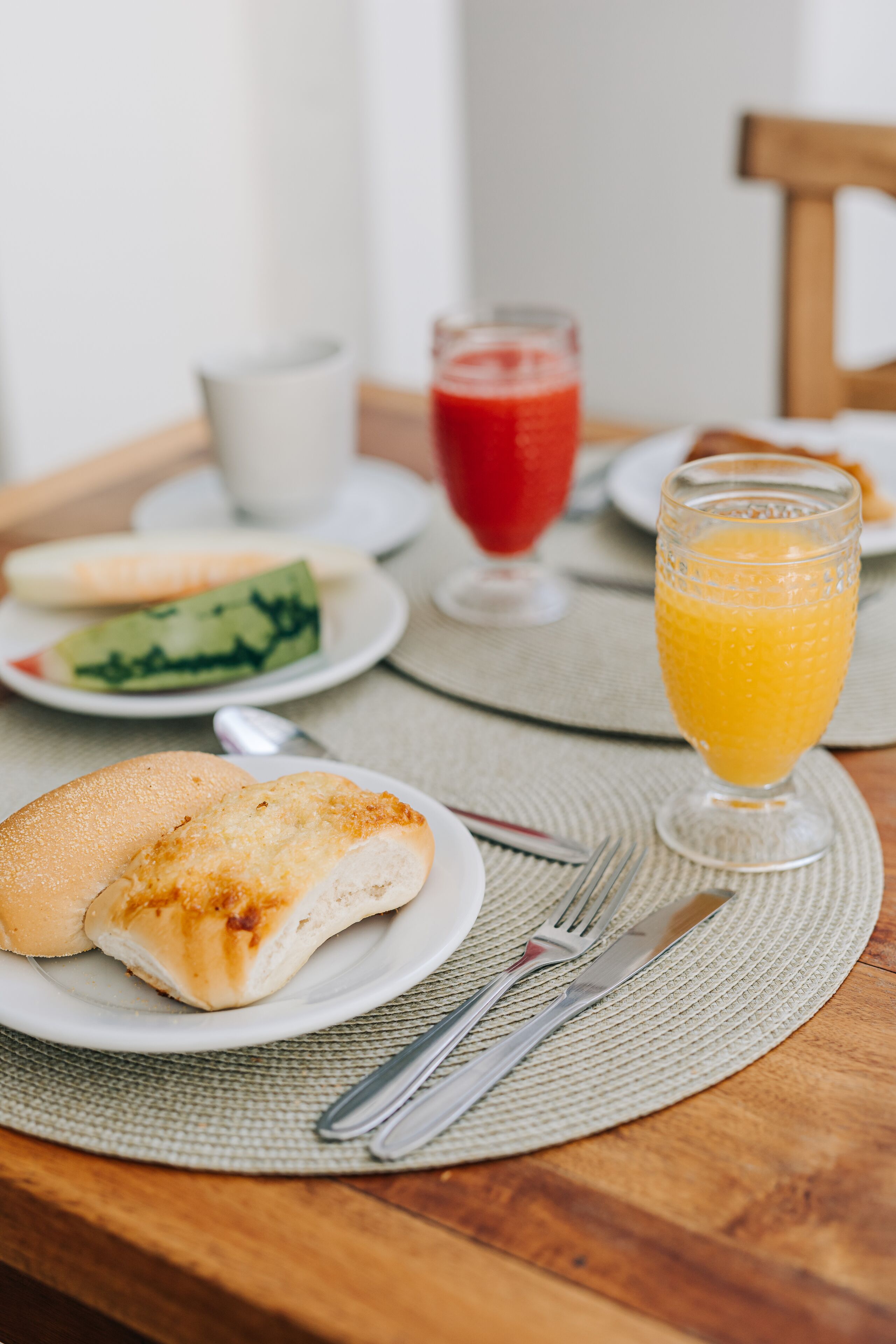 A breakfast setting with a plate of food, a glass of orange juice, and a cup of coffee on a wooden table.