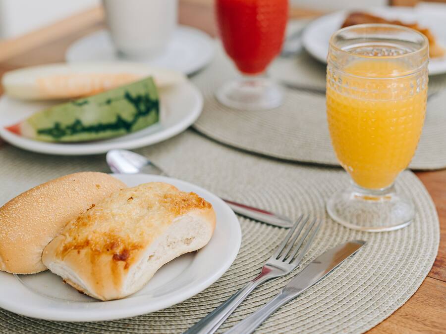 A breakfast setting with a plate of food, a glass of orange juice, and a cup of coffee on a wooden table.