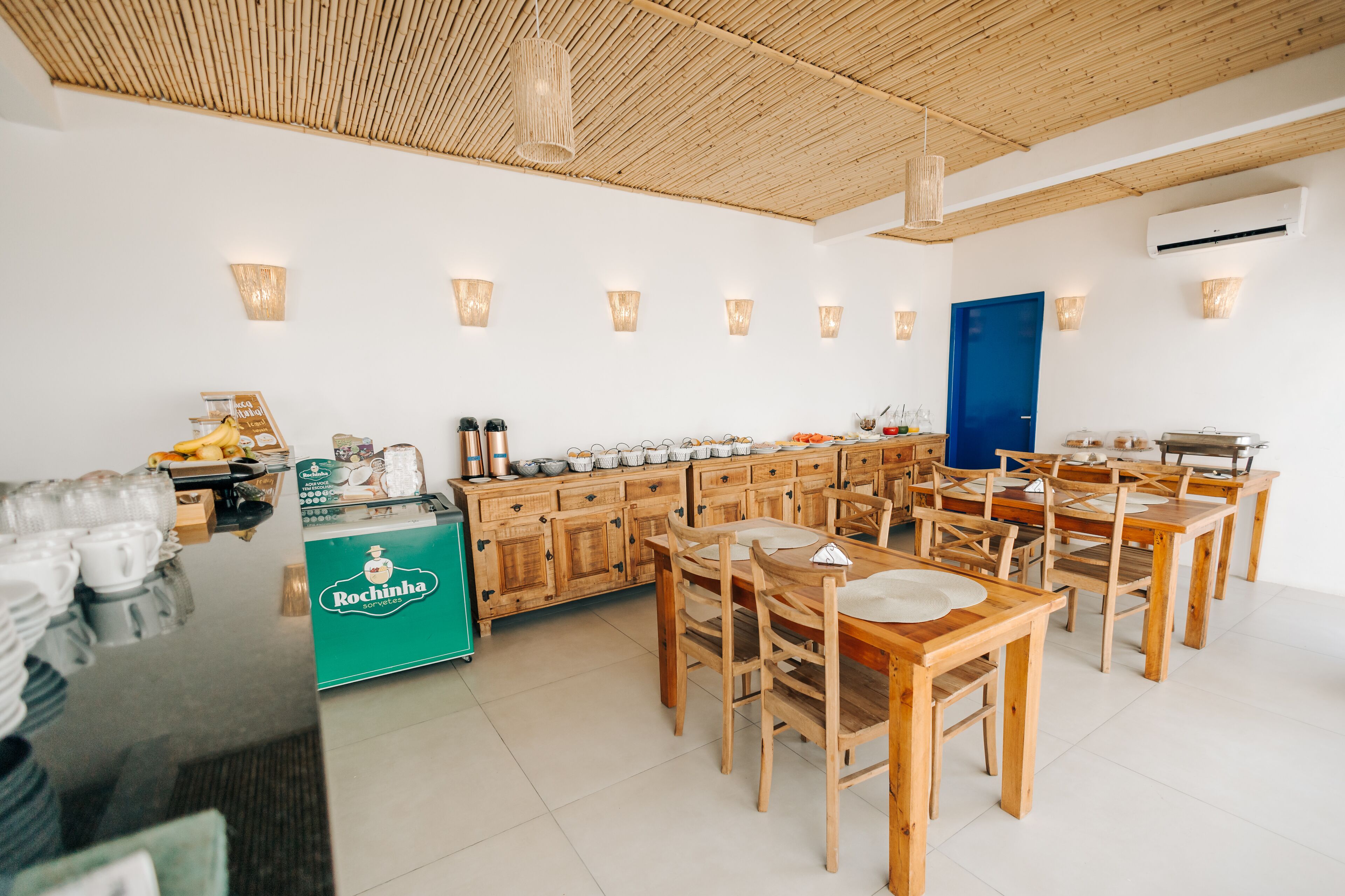 Een ruime eetruimte met houten tafels en stoelen, een buffet en wandlampen.
