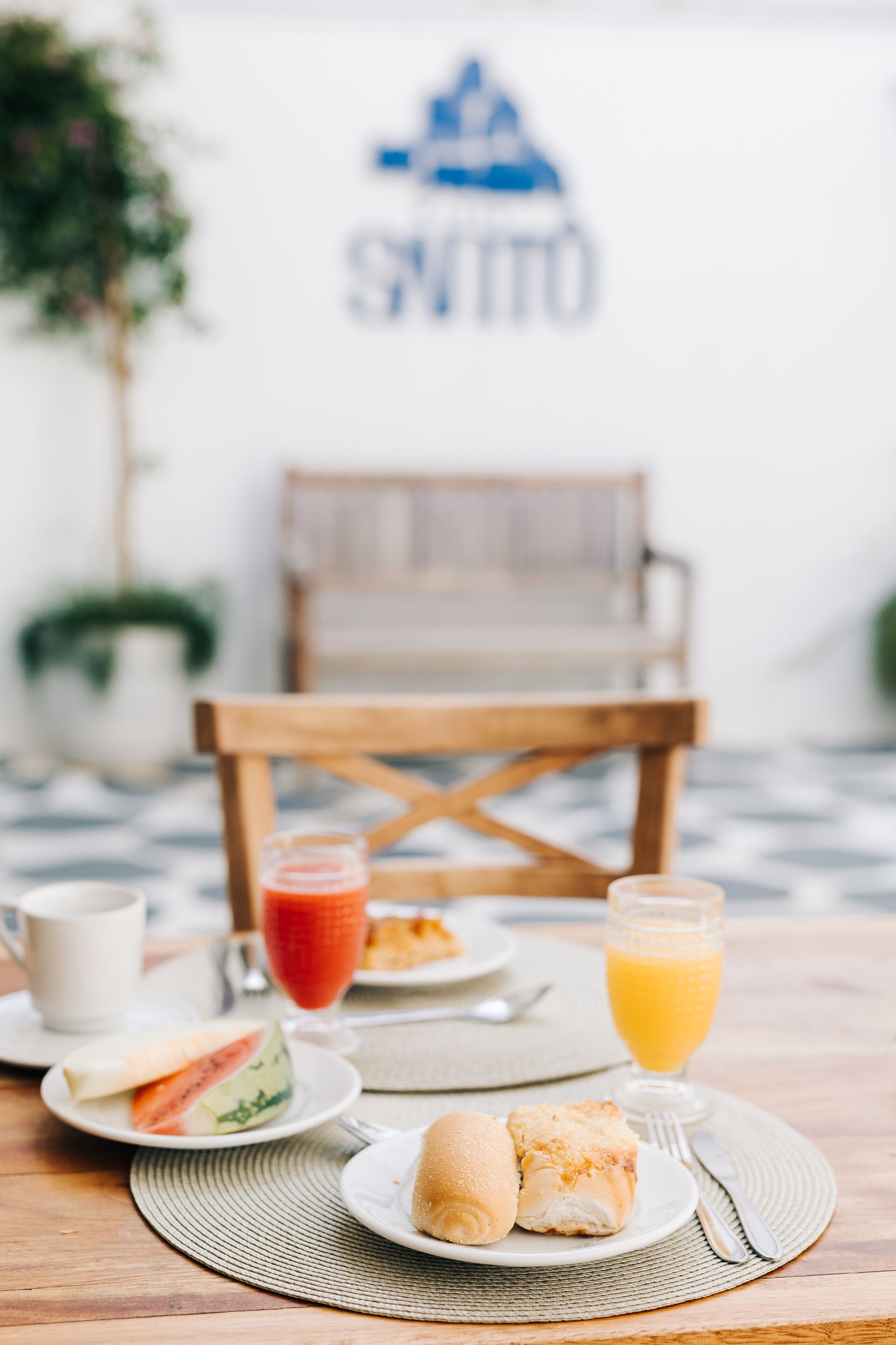 Una mesa de desayuno con un plato de croissants, un vaso de jugo de naranja y un vaso de jugo rojo.