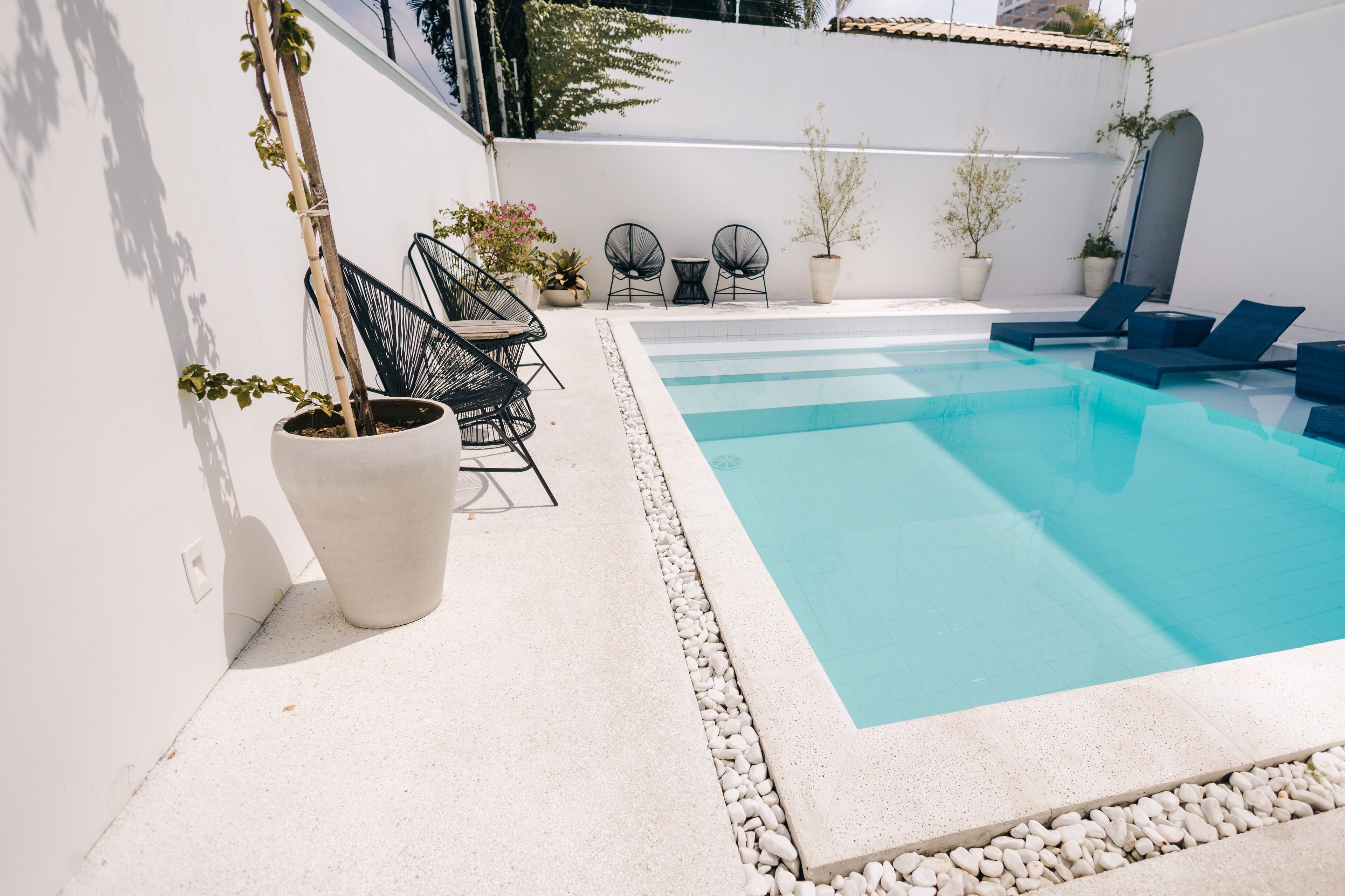 Una piscina con sillones de descanso y plantas en macetas.