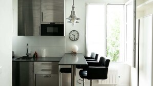 Een moderne keuken met roestvrijstalen apparatuur, een zwarte eettafel en een raam met uitzicht op groen.