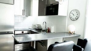 Een moderne keuken met roestvrijstalen apparatuur, een inbouwoven en een wandklok.