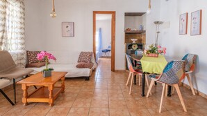 Un salon avec un canapé, une table basse en bois, une table à manger avec des chaises, et un coin cuisine à l’arrière-plan.