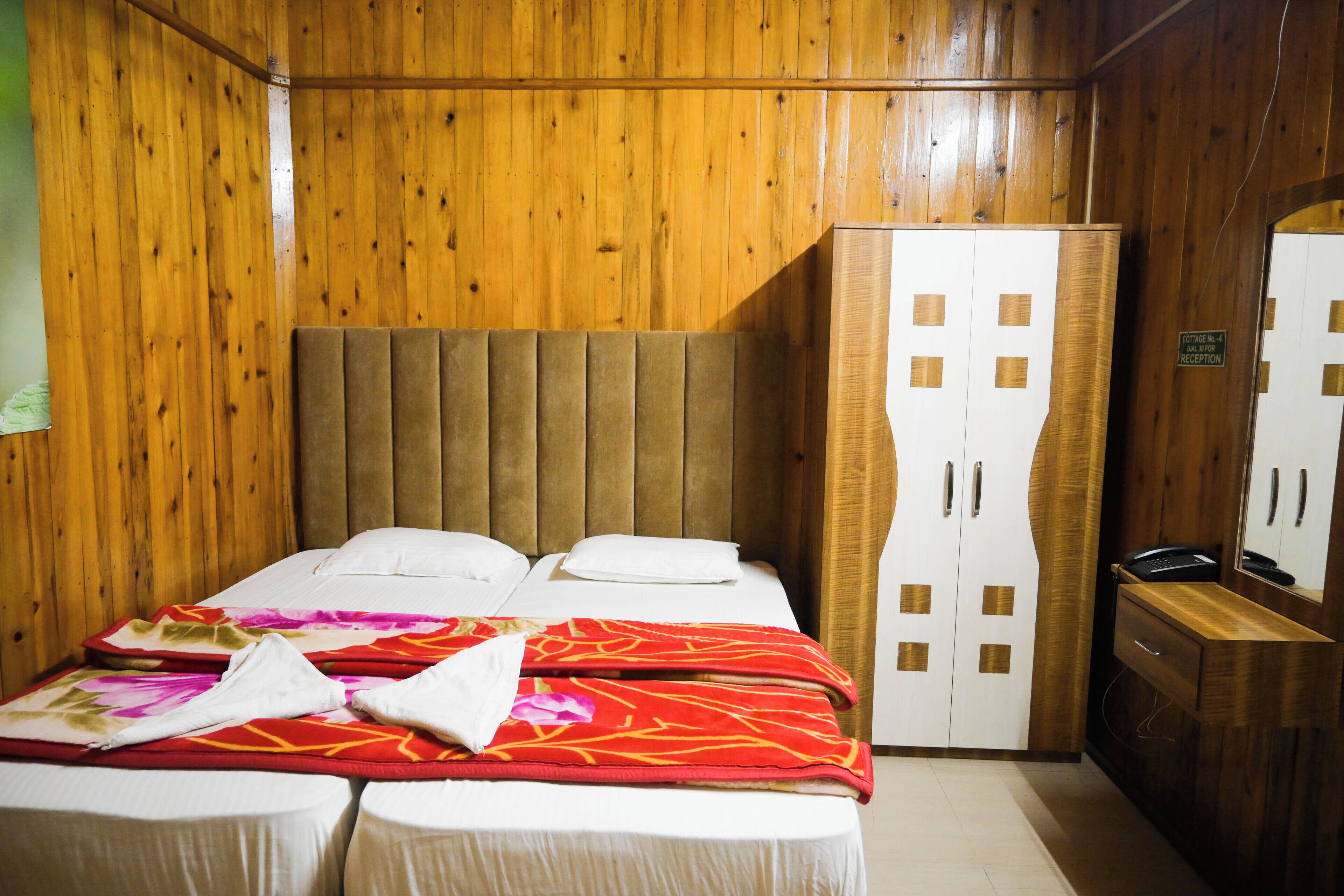 A wooden-paneled room with a bed, a wardrobe, and a mirror.