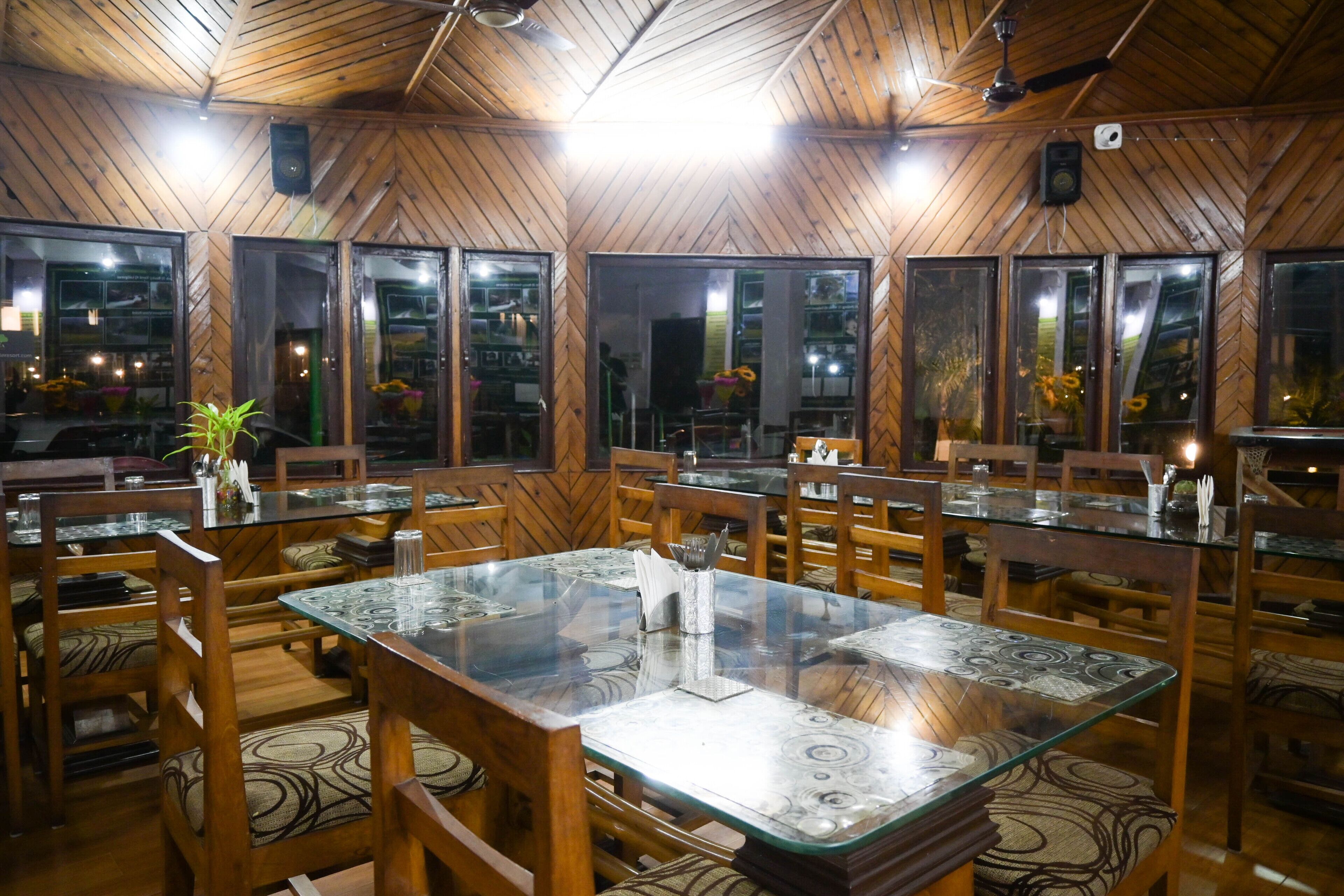 A restaurant with wooden walls and glass tables.