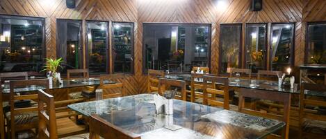 A restaurant with wooden walls and glass tables.