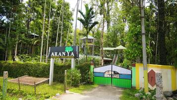 A sign for Aranya Goromara Jungle Resort surrounded by lush greenery and a gated entrance.