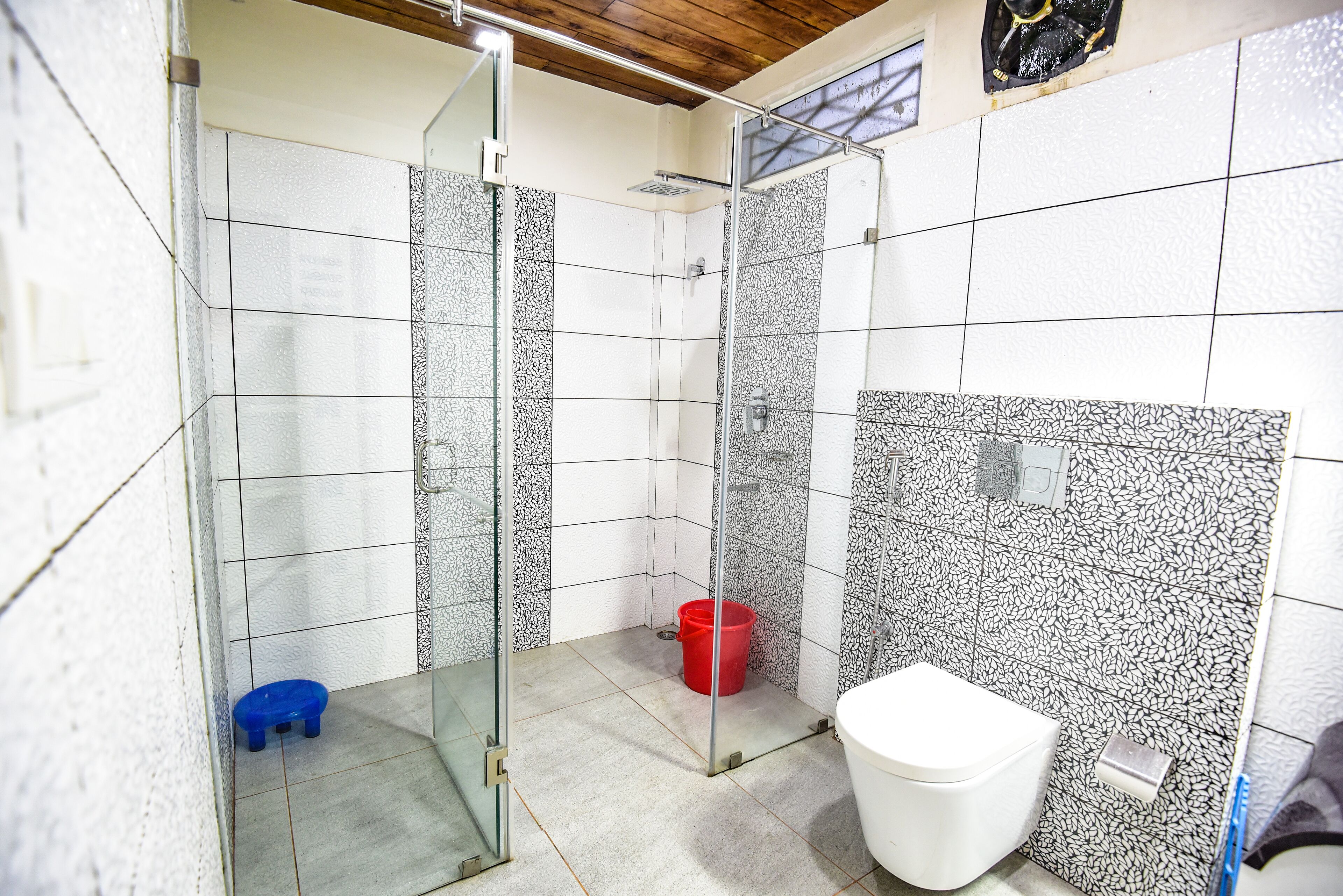 Une salle de bain avec une douche, des toilettes et un petit tabouret bleu.