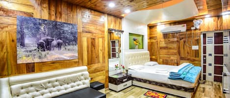 Habitación de estilo rústico con cama, banco, espejo y un cuadro de elefantes.