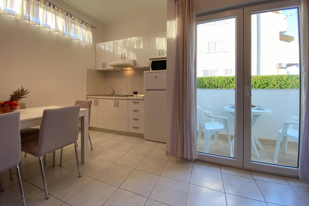Una cucina moderna con mobili bianchi, forno integrato e zona pranzo con tavolo e sedie.