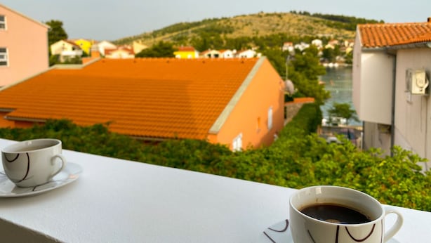 A balcony with two cups of coffee, overlooking a hillside with buildings. - Apartments Pulic (Zaboric)