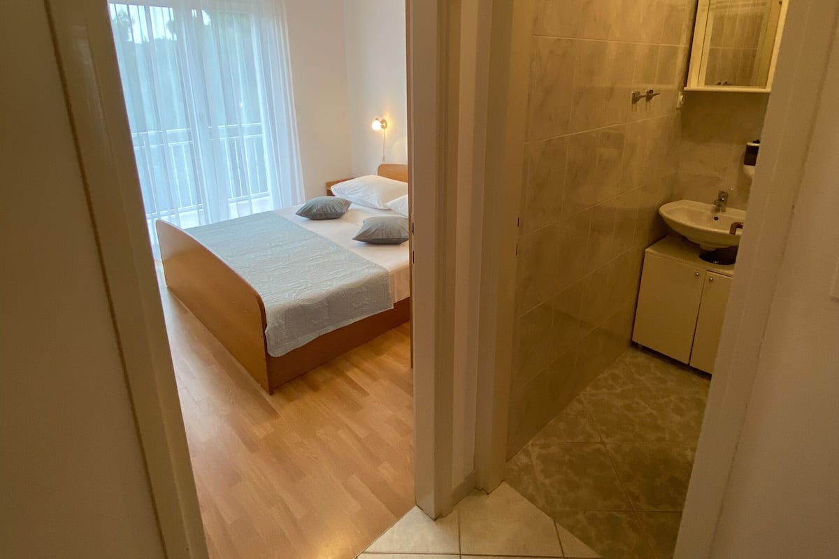 Una camera da letto con un letto, un comodino e una finestra con tende.