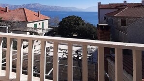 A balcony with a view of a coastal area, including houses and a clear blue sky. - Apartments Postira uz More (Postira)