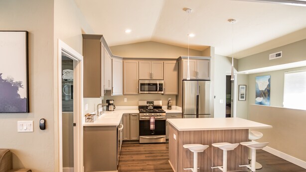Una cocina moderna con una isla central, electrodomésticos de acero inoxidable y suelo de madera.