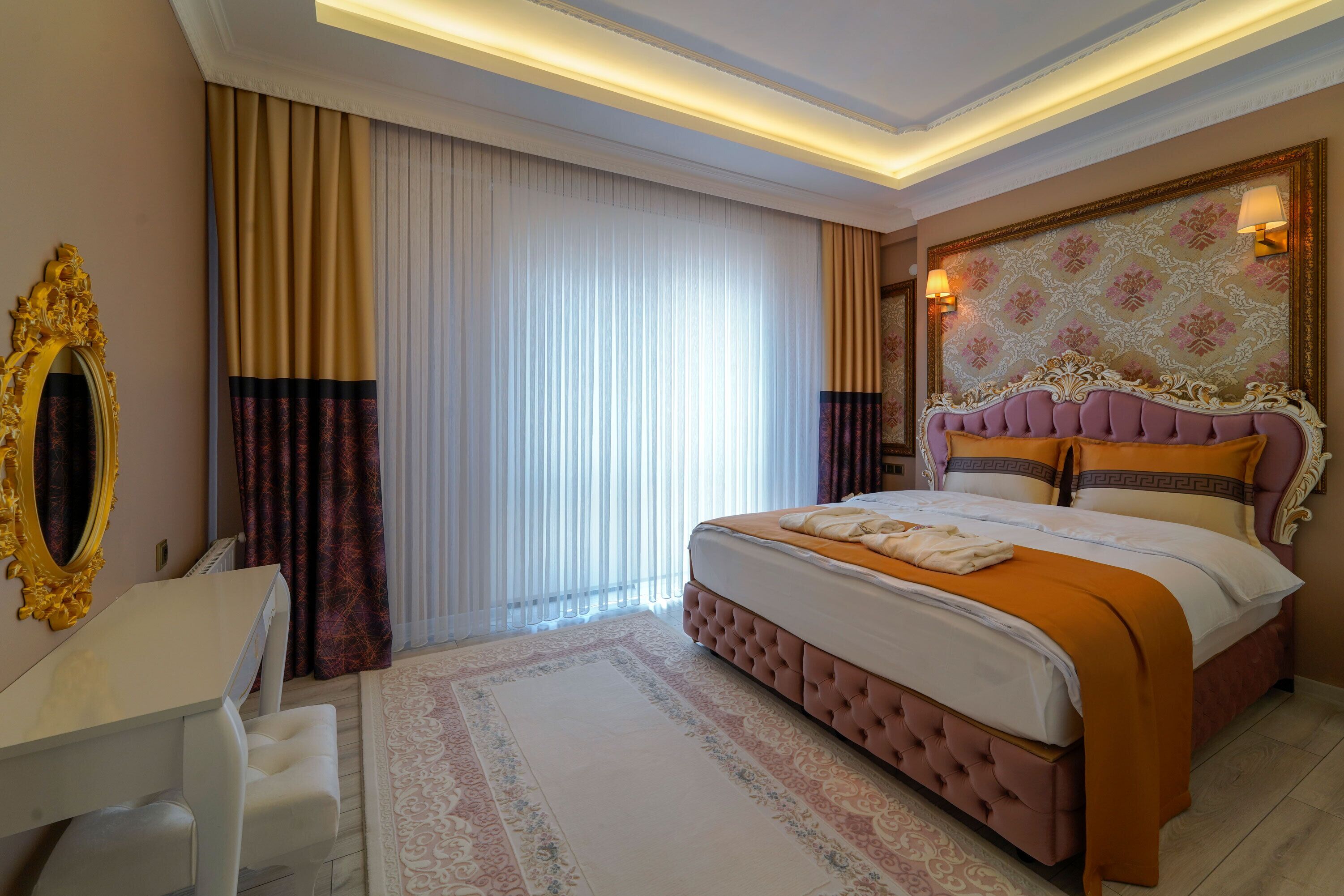 A hotel room with a large bed, a vanity with a mirror, and a desk.