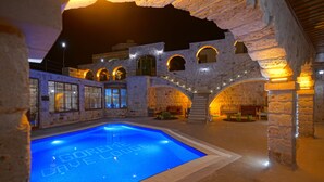 A swimming pool with "GORELLOVE LODGE" written on the water, surrounded by stone architecture and outdoor seating areas. - Göreme Cave Lodge (Nevsehir)