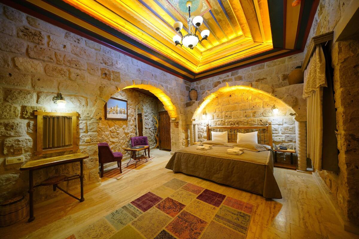 A room with a bed, a chair, a table, and a carpet.