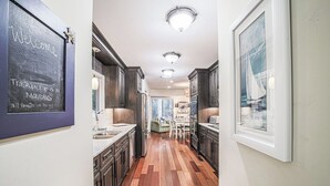 A modern kitchen with wooden flooring, dark cabinetry, and a chalkboard sign on the wall.
