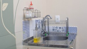 Una cocina con estufa a gas, lavamanos y un muro decorativo con diseño de hojas.