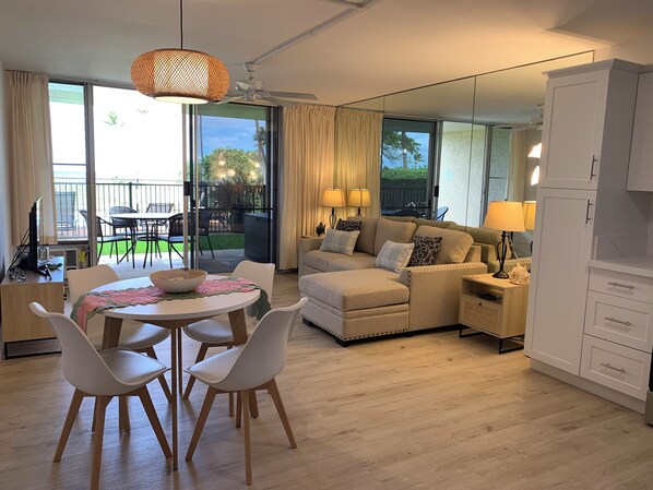 A modern living room with a sofa, chairs, a dining table, and a kitchen area.