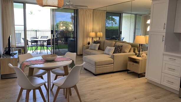 Ein modernes Wohnzimmer mit einer Couch, Sesseln, einem Esstisch und einer Küchenzeile.