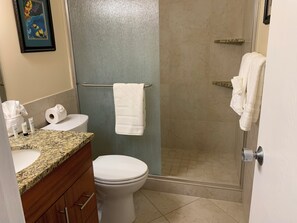 Une salle de bain équipée de toilettes, d’une douche et d’un lavabo, ainsi que d’articles de toilette.