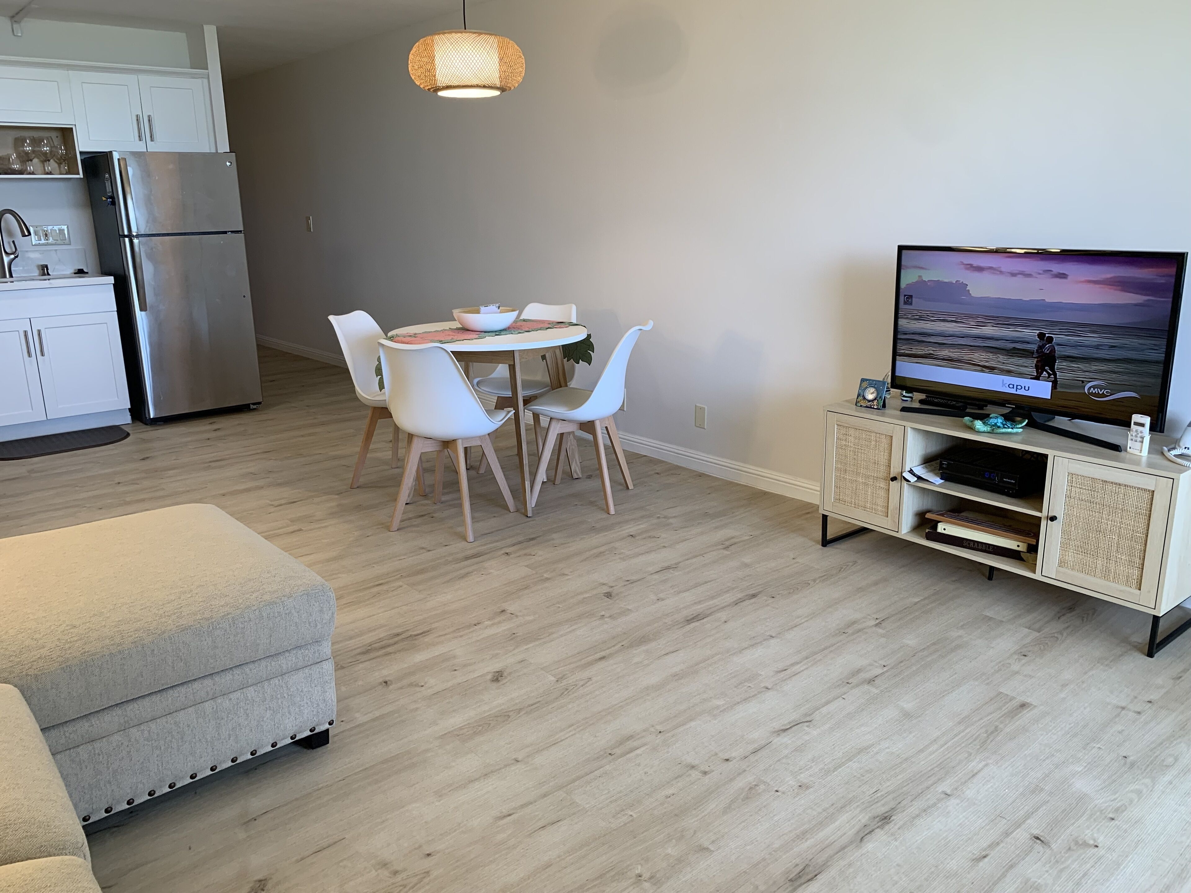 Un salon moderne comprenant un coin repas, un téléviseur à écran plat et une kitchenette.