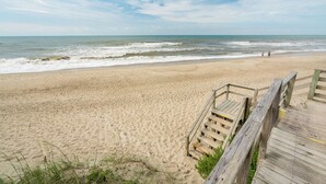 A sandy beach with a wooden boardwalk leading to the water. - Stunning Ocean Front Condo (Oceans 6) (Pine Knoll Shores)
