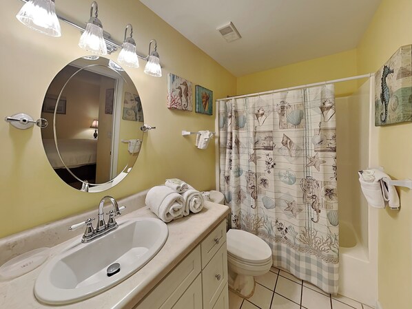 A bathroom with a sink, mirror, towel rack, and a shower curtain with a nautical theme.