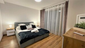 A modern bedroom with a bed, bedside tables, a nightstand, a wooden dresser, and a sign on the wall. - Pokoje Gościnne Magnas (Poronin)