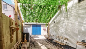 A courtyard with wooden benches and a blue door in the background.