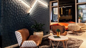 A modern interior with a textured wall, leather armchairs, a round coffee table, and a piano in the background. - Axis Porto Club Aliados (Porto)