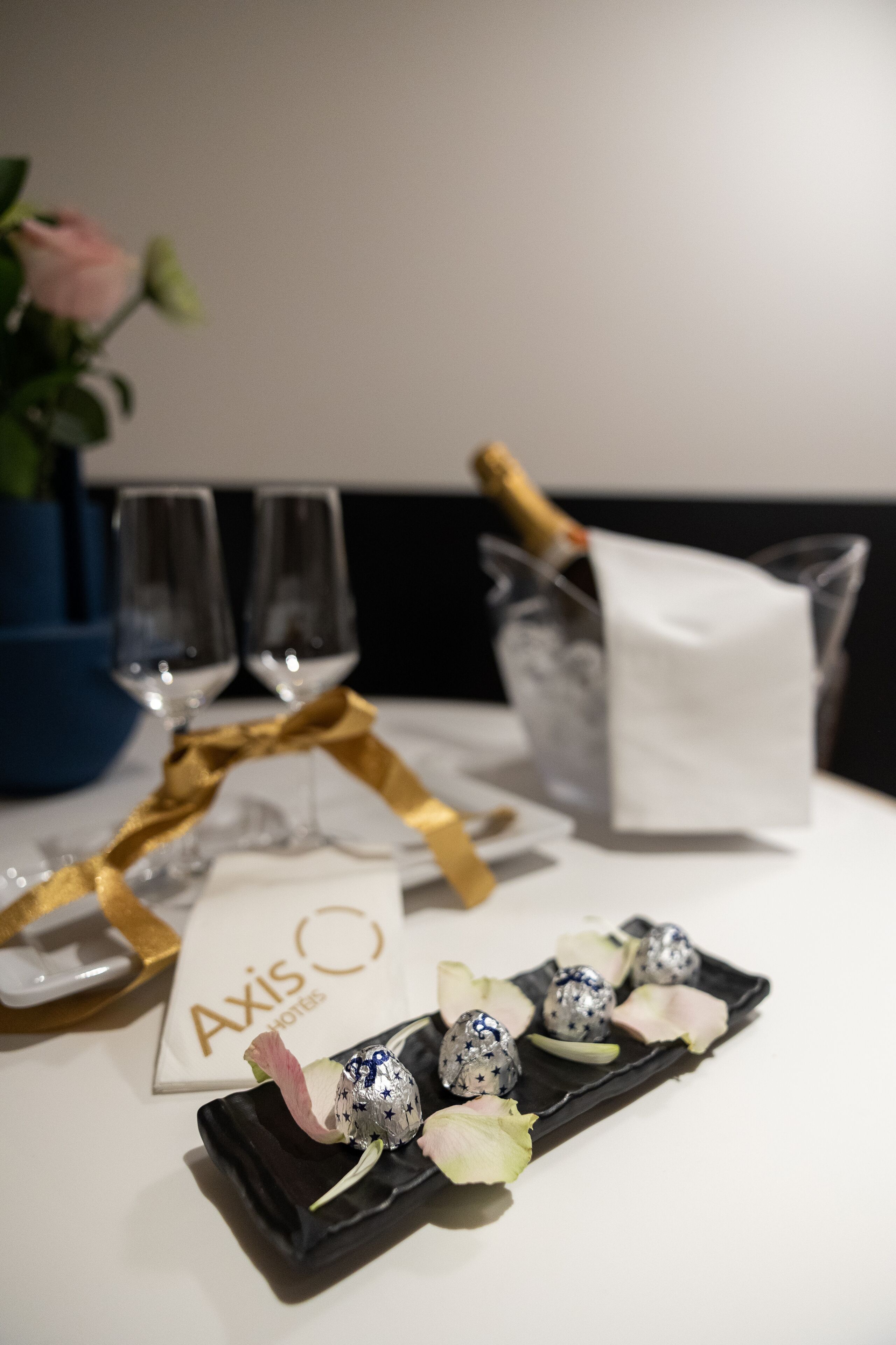 A table with champagne glasses, a bottle of champagne, and chocolates on a black tray.