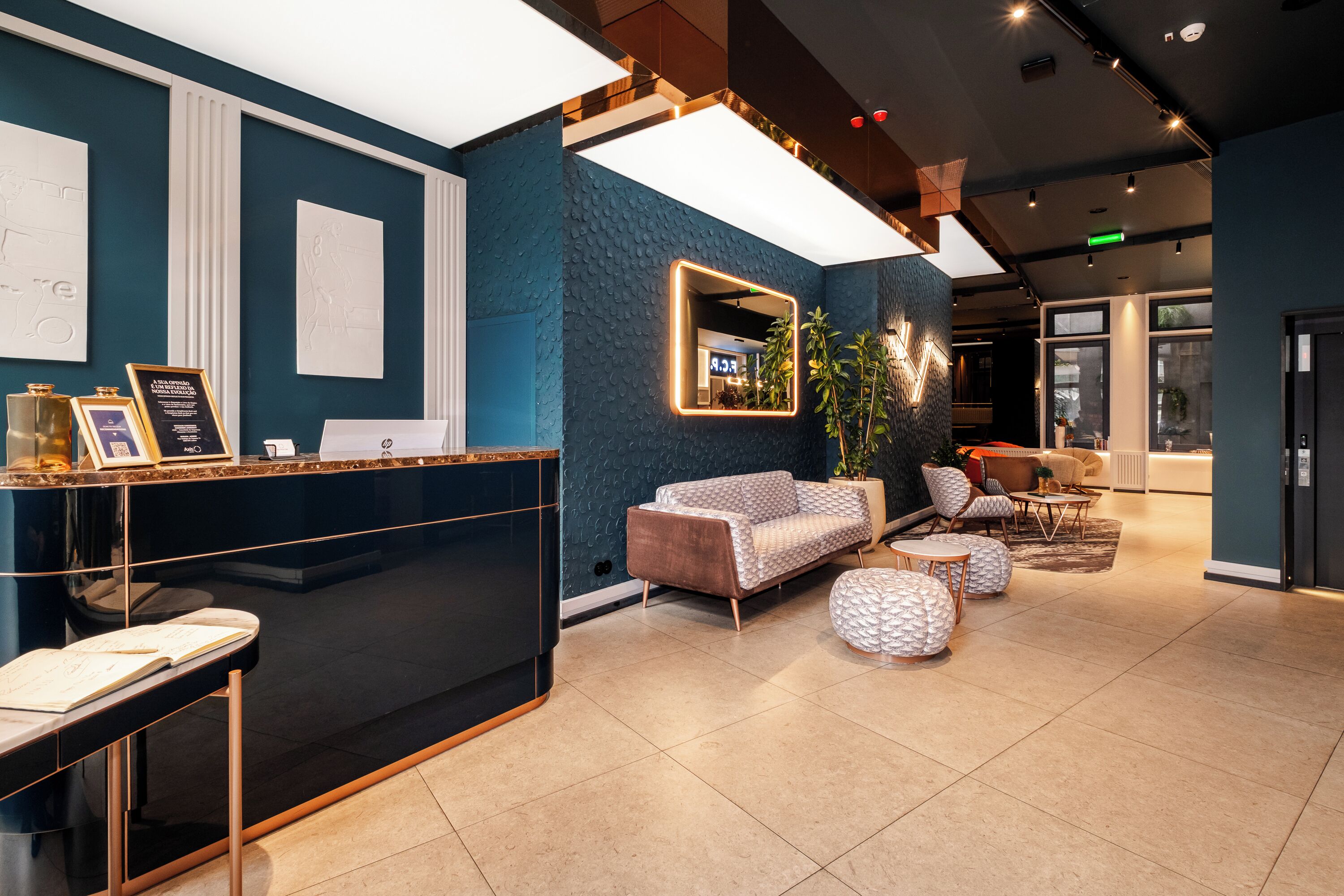 A reception area with a black reception desk, a blue textured wall, and a seating area with a sofa and ottomans.