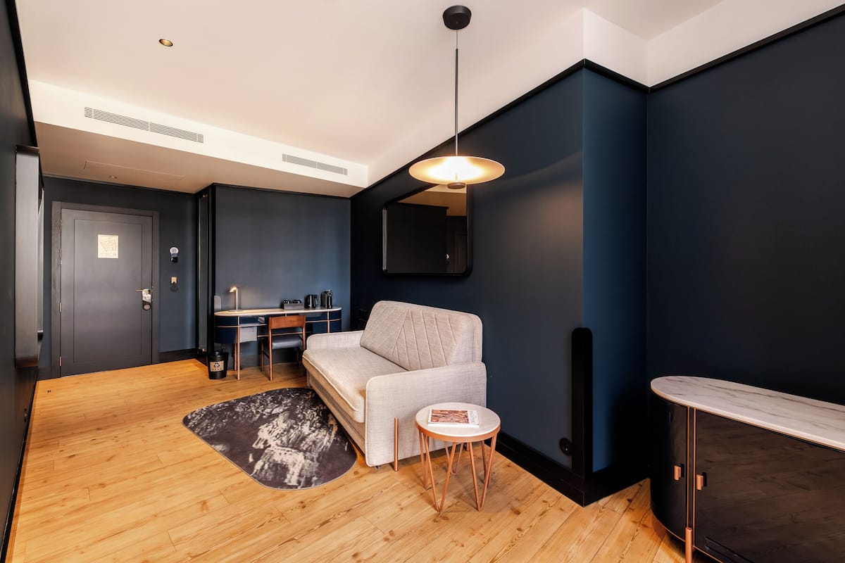 A modern living room with a sofa, a small round table, and a dark blue accent wall.