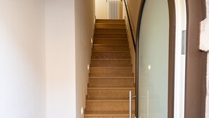 A staircase with a handrail, leading to a landing with a radiator.