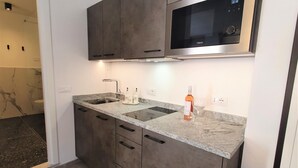 A modern kitchen with grey cabinets, a built-in microwave, a sink, and a countertop.