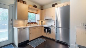 A modern kitchen with stainless steel appliances, wooden cabinets, and a built-in dishwasher. - Walk The Downtown Village of Winter Park!!! (Winter Park)