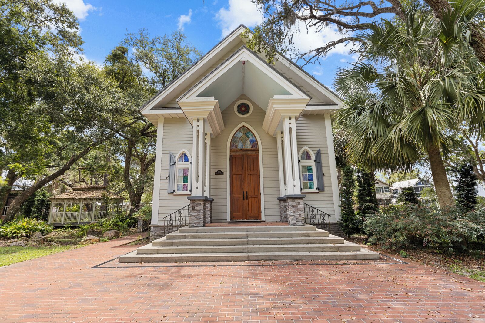 A small, single-story building with a gabled roof, a central entrance with a wooden door, and two arched windows on either side.