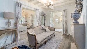 Une pièce spacieuse avec un grand canapé beige, un lustre et un miroir.