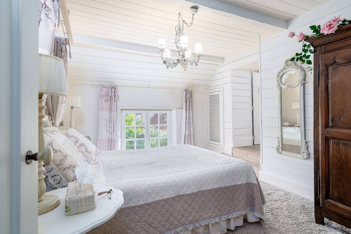 Een slaapkamer met een bed, een kaptafel, een spiegel en een kroonluchter.