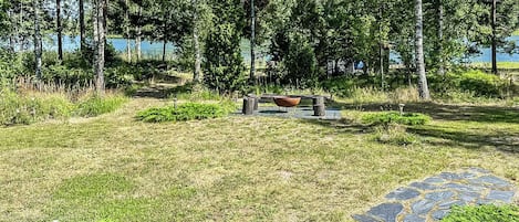 A grassy area with a stone pathway leading to a seating area with a fire pit.