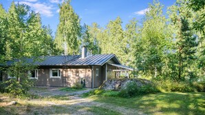 Een laag huis met een metalen dak, omringd door bebossing.